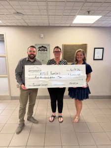 Three people holding a large check